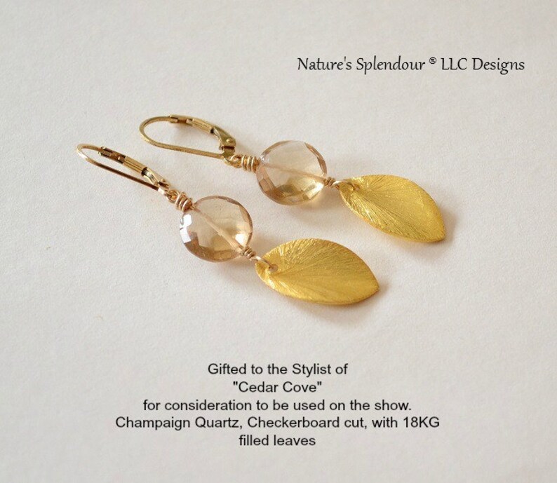 May include: Gold earrings with champagne quartz stones and gold leaf accents. The earrings are designed with a checkerboard cut and 18 karat gold filled leaves. The earrings are gifted to the stylist of "Cedar Cove".