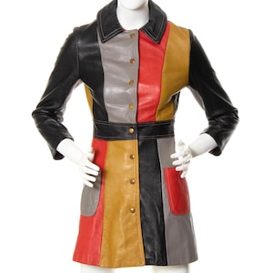 Può includere: Un abito corto in pelle multicolore con chiusura a bottoni sul davanti e una cintura nera. L'abito è realizzato con pannelli di pelle di diversi colori, tra cui nero, rosso, grigio e marrone.