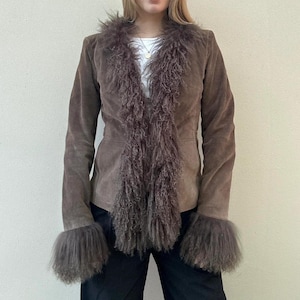May include: A brown suede jacket featuring a faux fur collar and cuffs. The jacket has a tailored fit and a button closure. The faux fur is a darker shade of brown, contrasting the suede. A stylish outerwear piece.