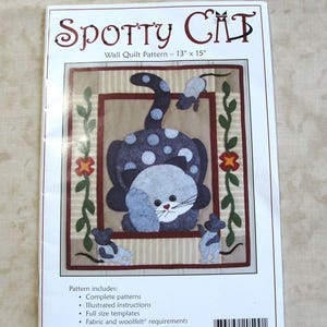 May include: A Spotty Cat wall quilt pattern measuring 13 inches by 15 inches. The cover features a dark blue cat with light blue spots, a white face, and three small grey mice. The text reads Spotty Cat, Wall Quilt Pattern, and includes a list of contents.