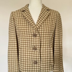 May include: A tan and cream-colored checkered blazer with a notched collar and three matching buttons. The jacket is displayed on a mannequin and has a classic, tailored design. The fabric appears to be a woven material.