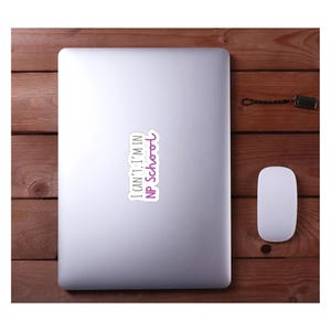 May include: A silver laptop computer with a white sticker on it that says "I can't, I'm in NP School". The sticker has purple text.