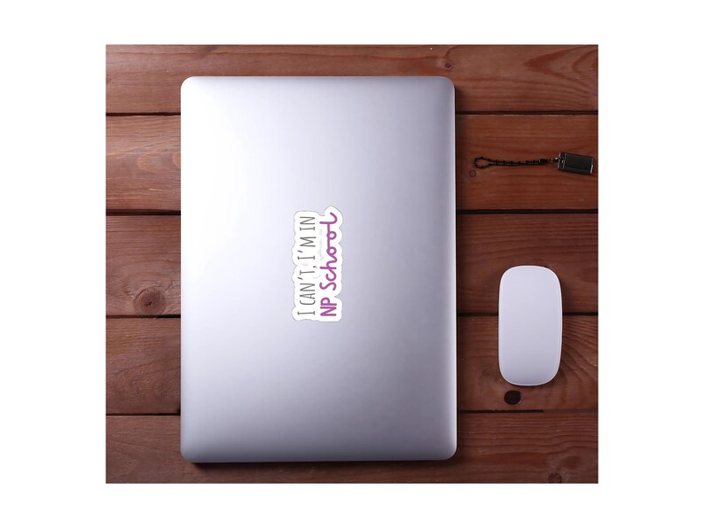 May include: A silver laptop computer with a white sticker on it that says "I can't, I'm in NP School". The sticker has purple text.