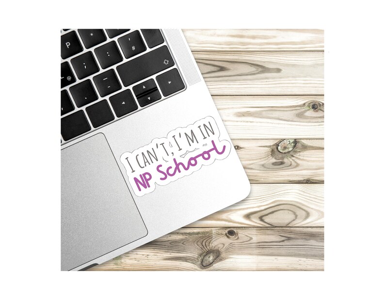 May include: A white laptop with a sticker that says "I can't, I'm in NP school". The sticker is on the top right corner of the laptop. The laptop is on a wooden surface.