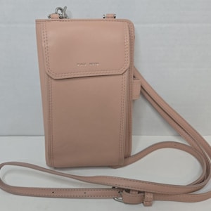 May include: A pale pink crossbody phone bag with a long, adjustable strap. The bag is rectangular with a flap closure and stitched detailing. The brand name "PIXIE MOOD" is visible on the front.