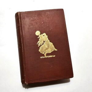 May include: A brown hardback book with a gold-colored illustration of a woman dancing on the front cover.