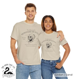 May include: Two people wearing sand-colored t-shirts with a skull graphic and the text "Van Helsing's Monster Hunting." The shirts also feature text about a Dracula collection. The shirts are Gildan brand.