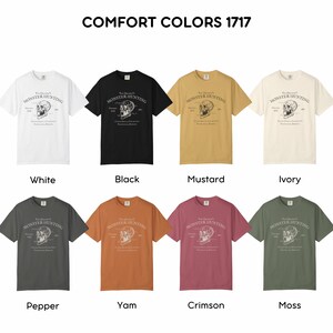 May include: A selection of Comfort Colors 1717 t-shirts in various colors, including white, black, mustard, and ivory. Each shirt features a graphic with the text "Monster Hunting" and a skull design. Additional colors are pepper, yam, crimson, and moss.
