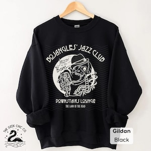 May include: Black sweatshirt with a white graphic of a skeleton in a fedora holding a microphone, with the text "BOJANGLES' JAZZ CLUB" and "DOWNSTAIRS LOUNGE". The sweatshirt also has the text "Jazz to the Bone" and "THE LAND OF THE DEAD".