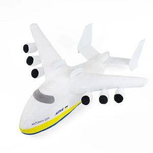 May include: White plush toy airplane with black engines and yellow and blue accents. The airplane has the text "ANTONOV 225" and "Mriya" on the side.