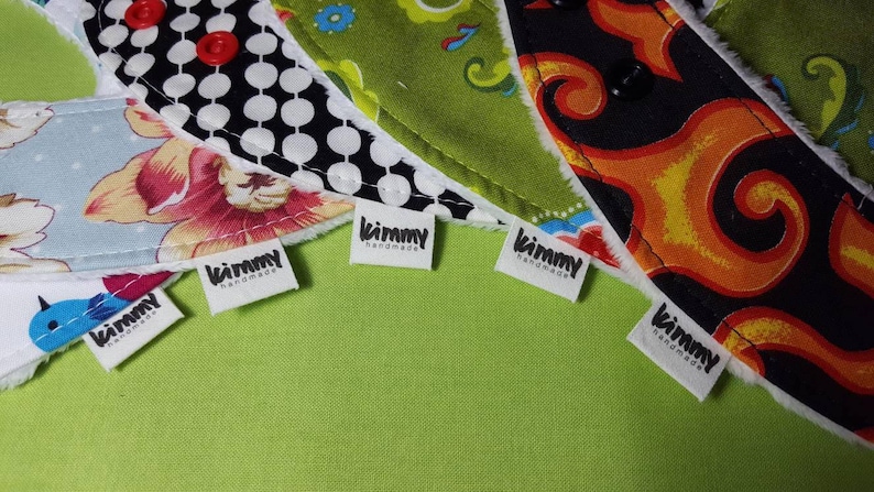 Puede incluir: Cinco etiquetas de tela blanca con texto negro que dice "kimmy handmade" est&aacute;n unidas a recortes de tela de colores. Los recortes de tela son de varios patrones, incluyendo floral, lunares y paisley.