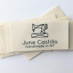 以下が含まれることがあります： 黒い文字とミシン図柄がついた白い布のラベルの束。テキストは「June Castillo handmade in NY」です。