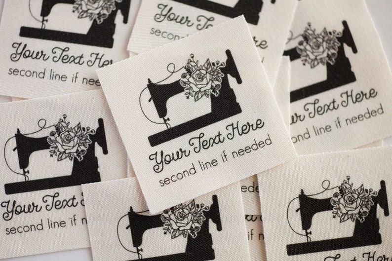 Peut inclure: Un ensemble d'&eacute;tiquettes en tissu blanc avec une machine &agrave; coudre noire et un motif floral. Les &eacute;tiquettes sont personnalisables avec le texte "Your Text Here" et une deuxi&egrave;me ligne de texte.