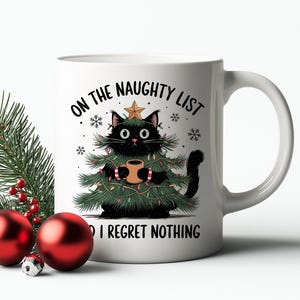 May include: White ceramic mug with a black cat wearing a Christmas tree costume, holding a mug. The mug has the text "ON THE NAUGHTY LIST & I REGRET NOTHING". Red Christmas ornaments and pine branches are on the left.