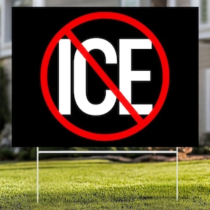 May include: A black yard sign with the white word "ICE" inside a red circle with a red slash. The sign is supported by a white metal frame and is placed on a green lawn.