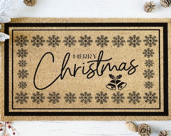 May include: A rectangular doormat with a natural coir fiber background and a black border. The words "Merry Christmas" are written in a stylish script, surrounded by snowflake designs. A pair of bells with holly accents are below the word Christmas.