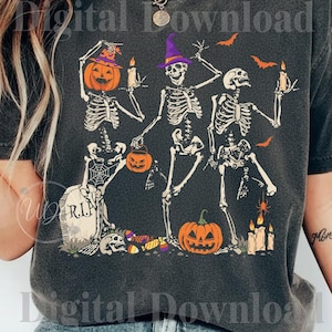 Peut inclure: Un t-shirt gris foncé avec un motif de trois squelettes dansants. L'un a une tête de citrouille, un autre porte un chapeau de sorcière violet et le troisième tient une bougie. Le dessin inclut une pierre tombale R.I.P., des citrouilles et des chauves-souris.