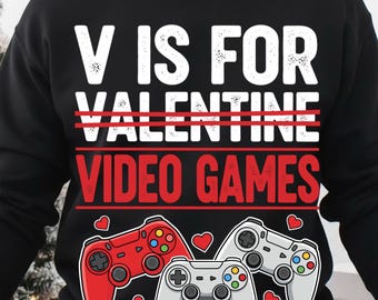 May include: A black crewneck sweatshirt featuring the white text V IS FOR VALENTINE and the red text VIDEO GAMES. The design includes three video game controllers in red, white, and grey, surrounded by small red heart icons across the chest area.
