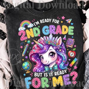 Peut inclure: Un sweat-shirt noir à col rond avec un motif coloré représentant une licorne portant une couronne de cristaux et un nœud papillon. Le texte indique I'M READY FOR 2ND GRADE BUT IS IT READY FOR ME? avec des dessins d'arc-en-ciel, globe, crayon, livre et règle.