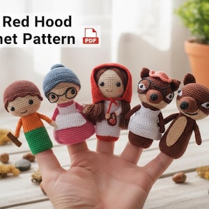 May include: A hand displaying crocheted finger puppets of characters from Little Red Riding Hood. The puppets include Little Red Riding Hood, the grandmother, a boy, and two animals. The text "Little Red Hood Crochet Pattern" is at the top.