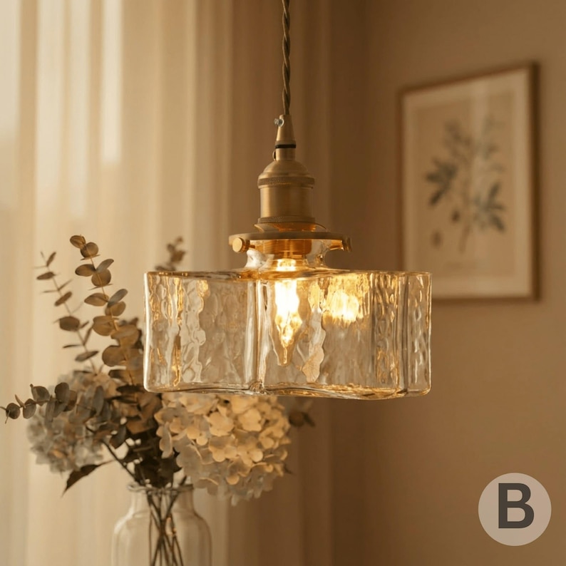 May include: A retro pendant light with a textured, rectangular glass shade. The light fitting has a brass-coloured metal base and a single bulb. The image shows the light fitting suspended from a cord, emitting a soft, warm glow.