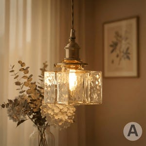 May include: A retro pendant light with a textured, square glass shade. The light fitting has a brass finish and a visible filament bulb. The image shows the light fixture suspended from a cord, with a vase of flowers in the foreground.