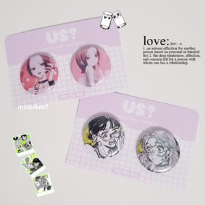 Puede incluir: Una colección de pines redondos y coloridos con ilustraciones de personajes de estilo anime. Los pines se muestran en tarjetas de color púrpura claro con el texto "US?" y "MI MI KO". La palabra "love" también es visible.