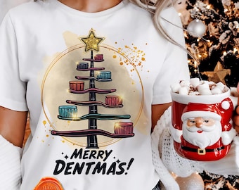 May include: White t-shirt with a Christmas tree design made of toothbrushes, a gold star, and the text "MERRY DENTMAS!". A red Santa mug filled with marshmallows is held in the hand.