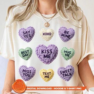Könnte beinhalten: Cremefarbenes T-Shirt mit neun gehäkelten Herzmotiven in verschiedenen Farben. Jedes Herz hat eine andere Botschaft, darunter "Say Yes", "XOXO" und "Kiss Me". Das Shirt trägt auch den Text "Digital Download - Hoodie & T-Shirt PNG".