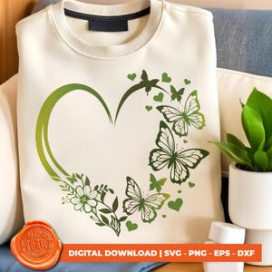 Op de afbeelding: Een wit sweatshirt met een groen hartontwerp en vlinders. Het hart is omlijnd met groen en gevuld met een gradiënt van groene tinten. De vlinders zijn groen en hebben een gedetailleerd ontwerp. De tekst "Made in Heart Studio" staat in een rode cirkel linksonder in de afbeelding.