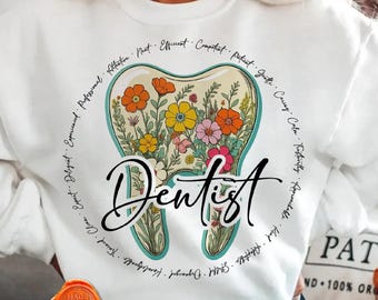 May include: White sweatshirt featuring a tooth-shaped design filled with colorful flowers. The word "Dentist" is written in cursive below the tooth. Surrounding the tooth are words like "Professional" and "Caring". The bottom of the image says "DIGITAL DOWNLOAD - HOODIE & T-SHIRT PNG".
