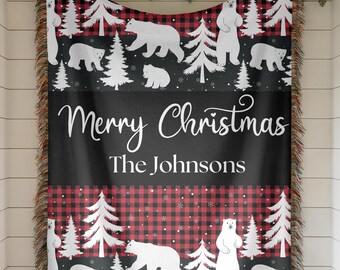 May include: A woven throw blanket featuring a red and black buffalo plaid pattern, white polar bears, and evergreen trees. The center black panel displays the white text Merry Christmas and The Johnsons. The blanket has fringed edges.