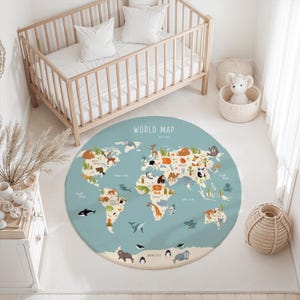 May include: A round area rug featuring a light blue world map with colorful illustrations of animals and plants across the continents. The text WORLD MAP is printed at the top center, with labels for oceans and continents in a simple white font.