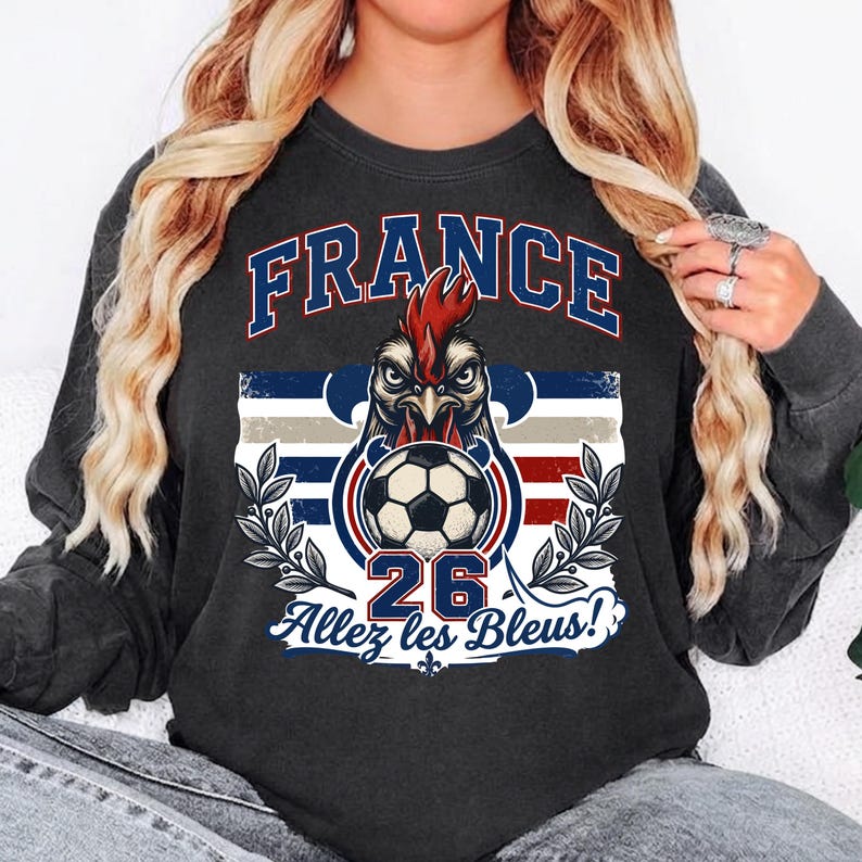 May include: Dark gray sweatshirt featuring a graphic of a rooster with a soccer ball, the word "FRANCE" in blue, and the text "26 Allez les Bleus!" in white. The design incorporates the colors of the French flag.