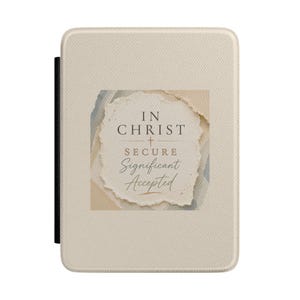 May include: A rectangular beige e-reader case with a textured surface. Centered on the front is a square graphic featuring torn-paper edges, displaying the text: IN CHRIST, SECURE, Significant, Accepted, with a small cross symbol between the lines.