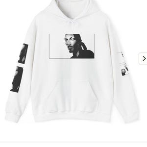 Peut inclure: Sweat-shirt &agrave; capuche blanc avec une image en noir et blanc d'un homme sur le devant. L'image est dans un cadre rectangulaire et l'homme regarde sur le c&ocirc;t&eacute;.