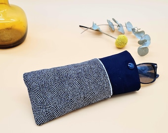 May include: A navy blue and white patterned eyeglasses case with a button closure. The case is made of fabric and has a white lining. A pair of sunglasses is inside the case.