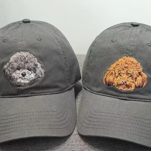 Peut inclure: Deux casquettes de baseball noires avec des images brodées de chiens. Un chien est gris et l'autre est brun.