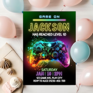 Könnte beinhalten: Eine lebendige Einladung mit einem neon-grünen und schwarzen Hintergrund, die eine farbenfrohe Gamecontroller-Grafik zeigt. Der Text lautet "GAME ON JACKSON HAS REACHED LEVEL 10" mit Veranstaltungsdetails: Samstag, 10. Januar, 14:00 Uhr und RSVP-Informationen. Pastellfarbene Ballons und dekorative Elemente umgeben die Einladung.