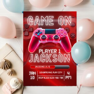 Puede incluir: Una invitación roja y rosa con temática de videojuegos con las palabras "GAME ON" y "PLAYER 1 JACKSON" en letras de neón blancas. La invitación incluye un gráfico de mando de juego y detalles del evento.
