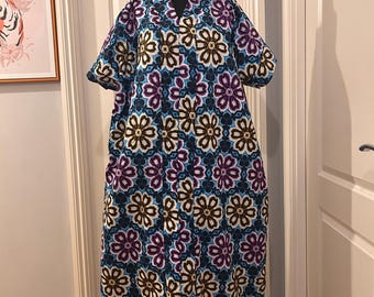 May include: A long, flowing dress with a floral print in shades of blue, purple, brown, and white. The dress has a V-neck and short sleeves.