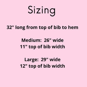 May include: Sizing chart for a bib, showing the length is 32 inches from the top of the bib to the hem. The medium size is 26 inches wide and 11 inches wide at the top of the bib. The large size is 29 inches wide and 12 inches wide at the top of the bib.