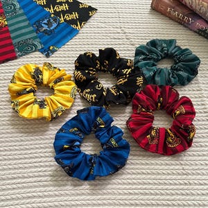 Puede incluir: Seis coleteros de tela en varios colores y estampados, con diseños y logotipos de la serie Harry Potter. Los coleteros son amarillos, negros, verdes, rojos y azules. También se ven muestras de tela y libros.