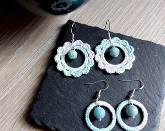 Puede incluir: Cuatro pares de pendientes hechos a mano. Dos pares presentan un diseño floral con un patrón de ganchillo azul claro y blanco, cada uno con una cuenta turquesa en el centro. Los otros dos pares son circulares, con una cuenta turquesa en el centro y un patrón de ganchillo azul claro y blanco.