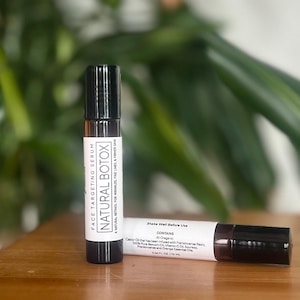 May include: Two small brown glass bottles with black roll-on tops. The bottles are labeled "FACE TARGETING SERUM NATURAL BOTOX" and contain a natural retinol for wrinkles, fine lines, and firmer skin. The label also says "Shake Well Before Use" and lists the ingredients as "All Organic Castor Oil that has been infused with Frankincense Resin, 100% Pure Bakuchi Oil, Vitamin C, Seabuckthorn, Frankincense and Orange Essential Oils".