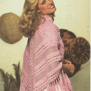 May include: A pink crocheted shawl with fringe. The shawl is draped over a person's shoulders and has a delicate, lacy pattern.