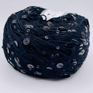May include: A ball of dark blue yarn with embedded silver sequins. The yarn is tightly wound, and the sequins are evenly distributed across the surface. This yarn is suitable for various crafting projects, such as knitting or crochet.