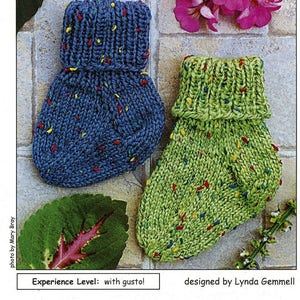 May include: A knitting pattern for "Little Speckled Toes #153" ankle socks for tiny toes. The pattern is designed by Lynda Gemmell and is described as "fast and easy" with an experience level of "with gusto!" The pattern is from Cabin Fever.