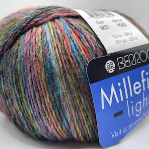 May include: A multi-coloured ball of Berroco Millefiori light yarn, with shades of red, blue, green, and purple. The label shows colour code 6821, dye lot 9543, 100g, and 320 m. This yarn is suitable for knitting and crochet projects.