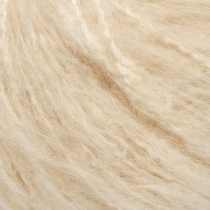 May include: Close-up of a soft, cream-colored yarn. The yarn is made of natural fibers and has a fluffy texture.